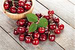 Ripe cherries on wooden table with green leaves