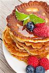 Pancakes with raspberry, blueberry, mint and honey syrup. On wooden table