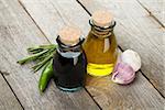 Olive oil and vinegar bottles with spices over wooden table background