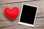Photo frame and valentines toy heart over wooden table background