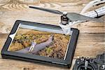 drone aerial photography concept - reviewing aerial picture (drone operator in a field) on a digital tablet with a drone rotor and radio control transmitter,