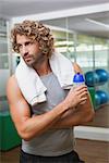 Handsome young man holding water bottle at the gym