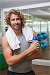 Portrait of a smiling handsome young man holding water bottle at the gym