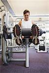 Fit man using weights machine for legs at the gym