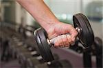 Fit man lifting heavy black dumbbell at the gym