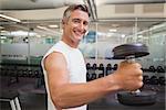 Fit man lifting heavy black dumbbell at the gym