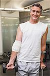 Injured man holding dumbbell in the weights room at the gym
