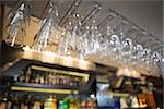 Many wine glasses hanging above the bar in a nightclub