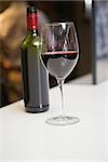 Close up of red wine into glass in front of the bottle in a bar