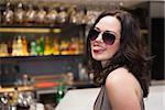 Pretty woman wearing sunglasses with tongue out at the nightclub