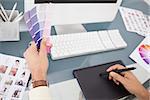 Designer working at desk using digitizer and colour sample in his office