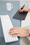 Designer using digitizer and typing on keyboard in his office