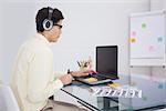 Businessman enjoying music and using laptop in his office