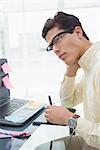 Designer with glasses thinking and using digitizer in his office