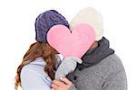 Couple in warm clothing holding heart on white background