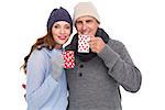 Happy couple in warm clothing holding mugs on white background