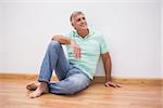 Mature man sitting on floor at home in the living room