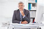 Smiling businessman at his desk in his office