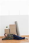 Happy man posing with moving boxes at home in the living room