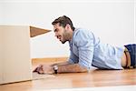 Smiling man looking inside cardboard box at home in the living room