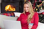 Woman doing online shopping with laptop and credit card at home in the living room