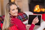 Smiling blonde shopping online with laptop at christmas at home in the living room