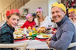 Smiling extended family in party hat at dinner table at home in the living room