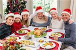 Portrait of smiling family sitting together at christmas dinner at home in the living room