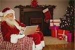 Santa using laptop on the couch at christmas at home in the living room