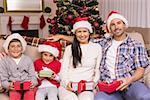 Festive family posing with gifts on the couch at home in the living room