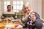 Smiling grandfather toasting at camera in front of his family at home in the living room