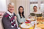 Cheerful family looking at camera during christmas dinner at home in the living room