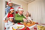 Grandfather in santa hat carving chicken at christmas at home in the living room