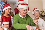 Grandfather in santa hat carving chicken at christmas dinner at home in the living room