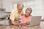 Senior couple looking up medication online at home in the kitchen