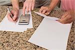 Senior couple paying their bills at home in the kitchen