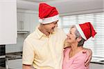 Senior couple wearing santa hats at home in the kitchen