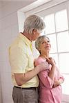 Senior couple looking out their window at home in the kitchen