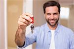 Casual man showing his house key in his new home
