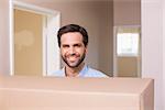 Happy man carrying moving box in his new home