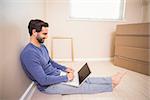 Casual man using laptop after moving in in his new home
