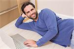 Happy man lying on floor using laptop in his new home