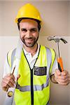 Construction worker holding spirit level and hammer in a new house