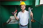 Construction worker holding spirit level and drill in a new house