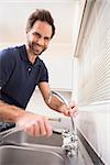 Plumber fixing the sink with wrench in the kitchen