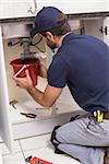 Plumber fixing under the sink in the kitchen