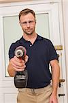 Handyman pointing power tool at camera in a house