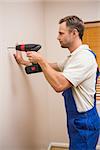 Construction worker drilling hole in wall in a new house