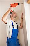 Construction worker drilling hole in wall in a new house