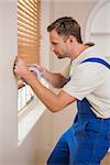 Man puting silver duct tape on the corners of the wall in a new house